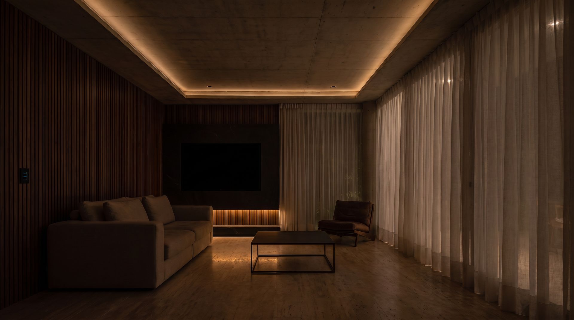 El mismo living en modo noche, con sólo una luz baja rozando el piso