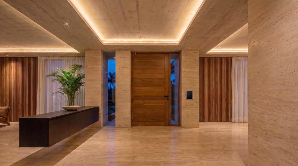 Hall de entrada con la iluminación de cornisa integrada en la losa de hormigón, las cortinas ocultas en el cielo raso y un panel de control empotrado al lado de la puerta