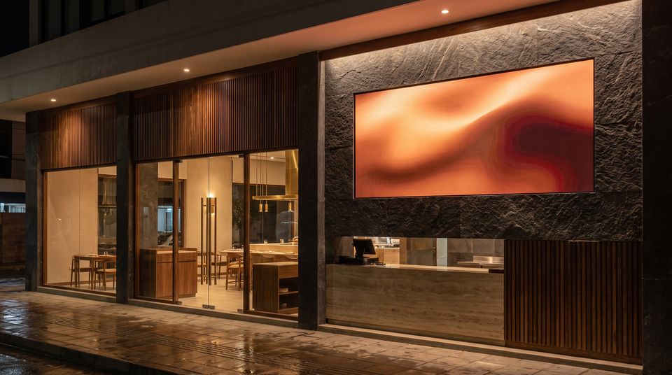 Pantalla LED integrada en la pared de piedra de un local gastronómico de noche