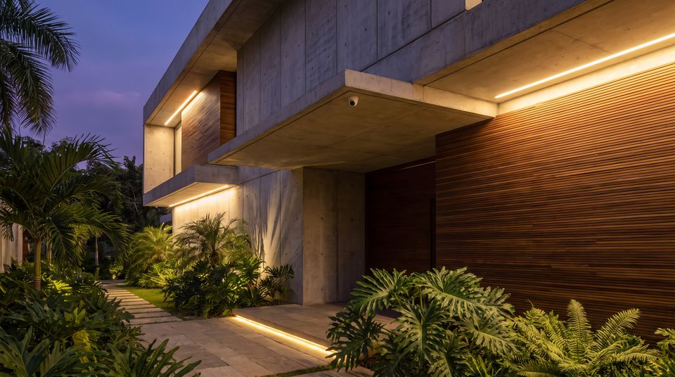 Fachada de una casa al atardecer con cámara discreta bajo el alero e iluminación perimetral