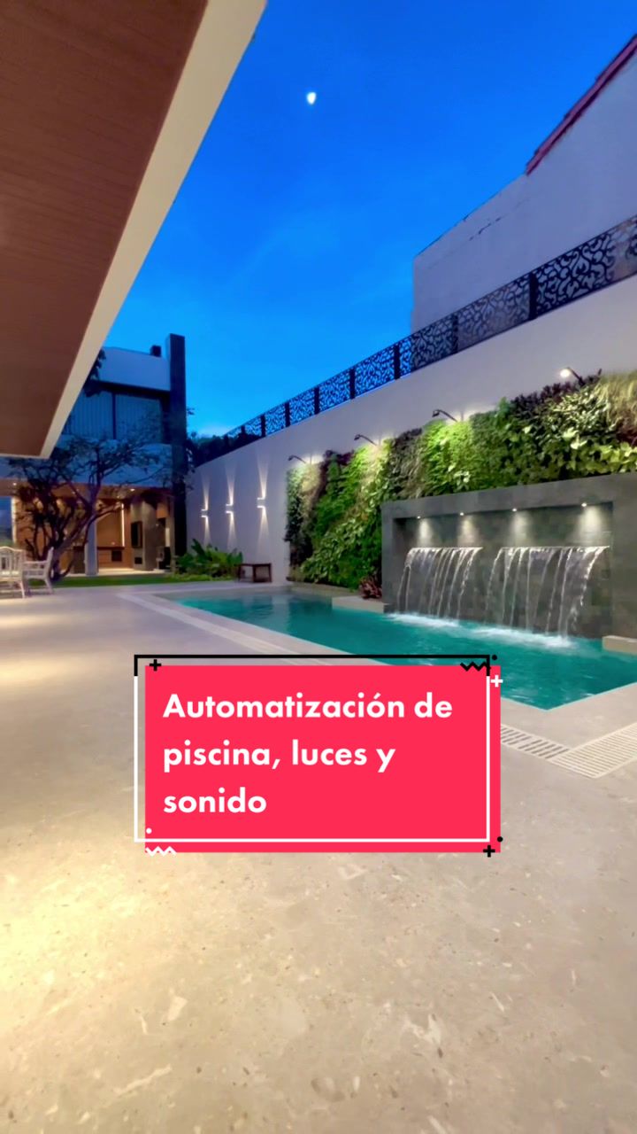 Piscina con cascadas, muro verde e iluminación automatizada a la hora azul